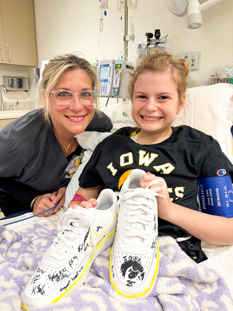 Gianna and one of her Nurses Holly smile with Nike shoes signed by the Iowa Football team