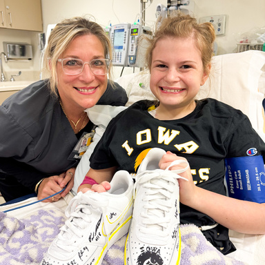Gianna and one of her Nurses Holly smile with Nike shoes signed by the Iowa Football team